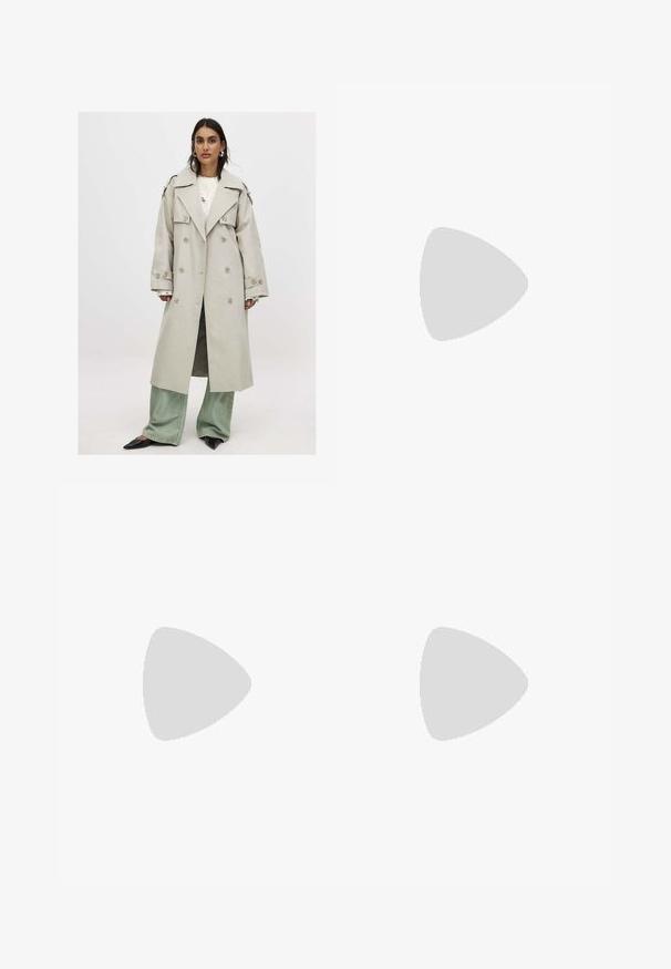 Ljusbeige dubbelknäppt trenchcoat med breda slag, knappränder och en avslappnad passform, lagrad över en stickad topp och gröna vida jeans.; Vit skräddarsydd topp i ribbat tyg med korta ärmar och rynkade detaljer på sidorna för textur och form.; Vita vida byxor i mjukt tyg. Har en elastisk midja med dragsko och en slät yta. Inga synliga mönster eller metalldetaljer.; Beige träningsskor med en blandning av nät och mockamaterial, rundad tå och snörning. Texturerade detaljer på ovandelen förbättrar greppet.