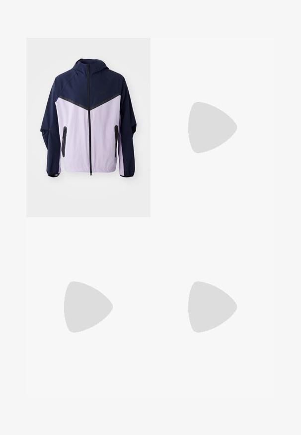 Veste légère Nike, blocs de couleurs marine et violet clair, fermeture éclair sur le devant, capuche, équipée de fermetures éclair noires et d'un design en demi-panneau sur les épaules.; T-shirt en coton blanc à manches courtes et col rond. Présente un petit logo Nike subtil sur la poitrine et une étiquette sur le côté.; Pantalons en denim noir avec une coupe droite, dotés d'une fermeture à bouton et à zip, de passants de ceinture et de coutures minimales.; Baskets en cuir blanc avec logo Nike vert, bout rond, semelle plate, associées à un pantalon en denim bleu clair, présentées sur un tapis bleu.