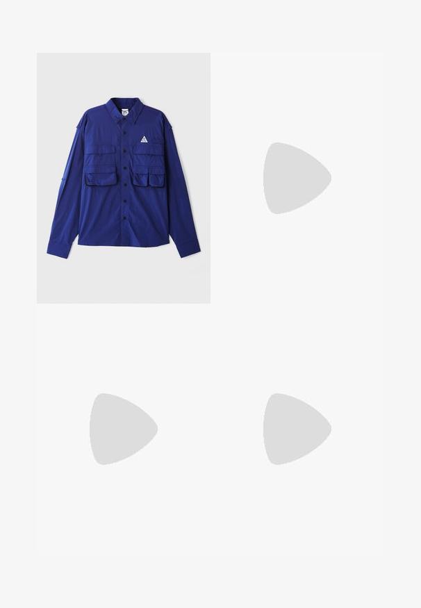 Blue long-sleeve shirt with two chest pockets, button-up front, and a triangular logo on the left side. Made from lightweight fabric.; Cream-colored cotton t-shirt with short sleeves, featuring "NIKE SB" in black and red text on the chest. Standard round neckline.; White slim-fit jogger pants with elastic waistband and drawstring, featuring side seam detailing and a small black patch on the right leg.; White athletic sneaker featuring a smooth upper, lace closure, cushioned sole, and a visible air unit with red accents on the branding.