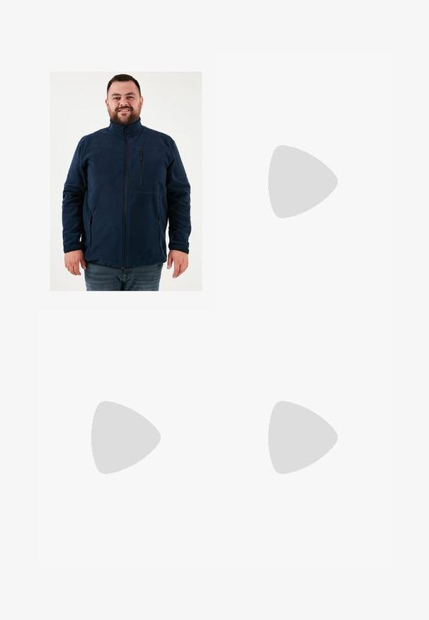 Tengerészkék fleece dzseki magas gallérral, elülső cipzárral és cipzáras zsebekkel. Simaság jellemzi, valamint testhezálló fazonnal bír.; Két pólóing: az egyik sötétkék, a másik fehér, mindkettőn kicsi piros, fehér és kék díszítés található a mellzsebből és a galléron.; Sötétkék farmernadrág, testhezálló fazonnal, finom áttűnéssel, öt zsebbel és fémből készült gombzárral. Kontrasztos színű varrási díszítések.; Fehér sportcipő sima bőr felsőrésszel, fűzős elülettel, perforált orral és mintázott talppal. Minimalista dizájn három oldalsávval.