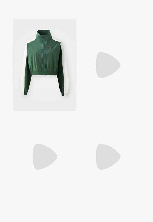 Veste verte courte avec un col montant, des manches blanches contrastantes, une fermeture éclair et une taille élastique. Logo Nike sur la poitrine.; Top court côtelé vert avec de fines bretelles, doté un ourlet festonné et d'un tissu texturé. Aucun matériel ou motif proéminent.; Pantalons de survêtement blancs en tissu doux, dotés d'une taille élastique grise avec le logo "Nike", d'un cordon de serrage et de fentes sur les côtés.; Baskets Nike argentées avec une finition lisse et brillante, lacets noirs et bande Velcro. Portées avec des chaussettes côtelées de couleur crème.