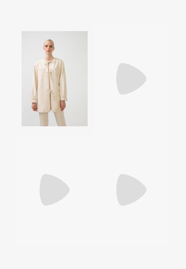 Giacca beige a maniche lunghe realizzata in tessuto morbido, con due tasche frontali, chiusura con cinturino e vestibilità rilassata con maniche arricciate.; Top cropped bianco a coste con spalline larghe e scollatura rotonda. Presenta una texture morbida e un design minimalista senza motivi.; Pantaloni sportivi marroni con elastico in vita, due tasche laterali e un piccolo logo sul lato sinistro, realizzati in un tessuto morbido.; Scarpa da barca in pelle marrone con suola in gomma marrone robusta, occhielli dorati e cuciture a contrasto. Presenta un logo sul lato.