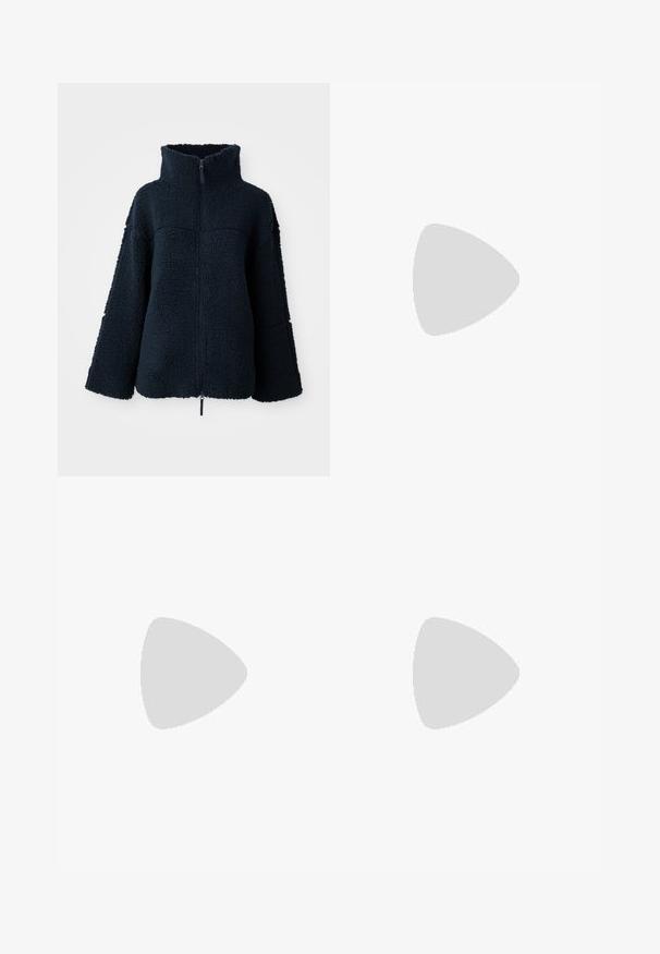 Marineblå tekstureret fleecejakke med høj krave og fuld frontlynlås, lange ærmer og løs pasform.; Tre langærmede toppe stablet: sort, grå og hvid. Hver har en rund halsudskæring og et cropped design med glat, let stof.; Sorte flared bukser lavet af strækbart stof, med en høj talje og flared manchetter med sideskår for ekstra bevægelse.; Grå ruskinds sneakers med hvide snørebånd, sorte striber og en hvid gummisål. Har et rundt logo på tungen og en gummisål.