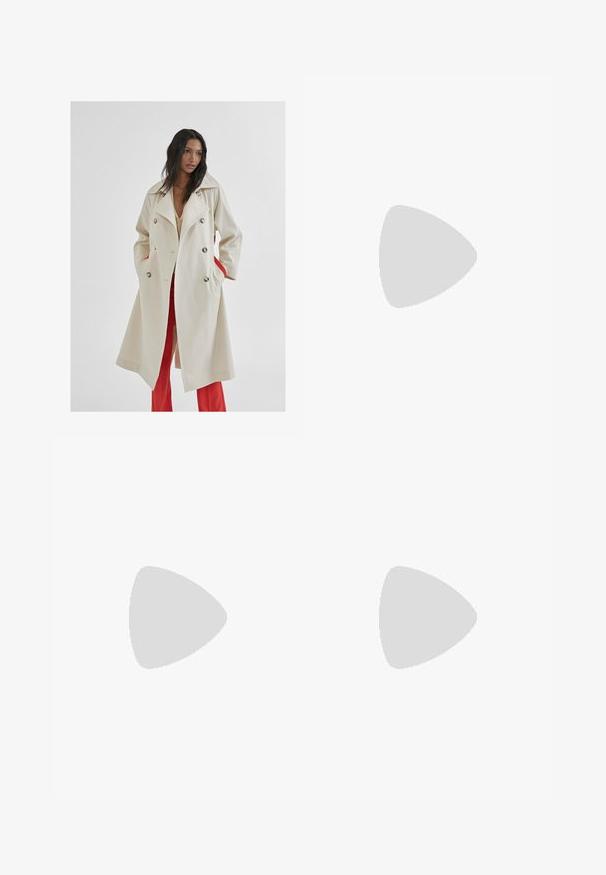 Beżowy płaszcz typu trench z podwójnym zapięciem, dużym kołnierzem, bocznymi kieszeniami wyłożonymi czerwonym materiałem oraz srebrnymi guzikami. Gładki materiał o wyraźnej strukturze.; Czarna bawełniana koszulka z luźnym krojem, krótkimi rękawami, okrągłym dekoltem i gładką fakturą. Bez widocznych wzorów ani akcentów.; Khaki bawełniane spodnie o prostym kroju, z zapięciem na guzik z przodu, dwiema bocznymi kieszeniami i minimalistycznym logo z przodu.; Kremowe i lawendowe trampki z trzema paskami oraz teksturowaną brązową podeszwą, wyposażone w sznurówki i wyścieloną piętę. Górna część z miękkiego materiału.