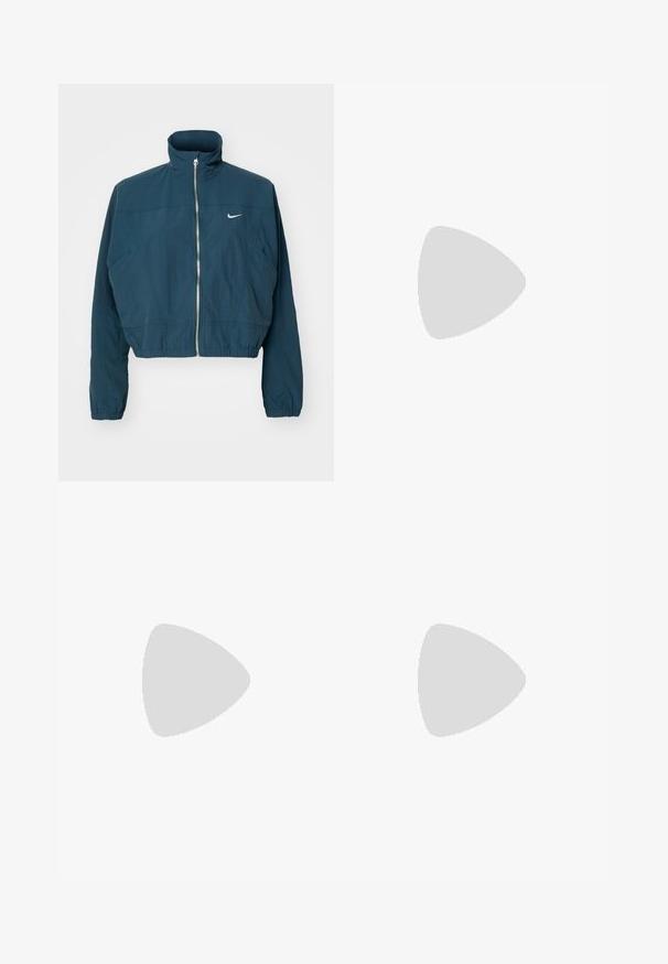 Veste cropped bleu marine avec un col haut, fermeture éclair à l'avant, poignets élastiques et un logo Nike blanc sur la poitrine gauche. Texture lisse.; T-shirt noir en coton. Manches courtes et col rond. Présente un petit logo sombre sur la poitrine gauche. Design simple et classique.; Jean large taille haute en denim bleu moyen, avec un effet délavé, un design de poches traditionnel et une fermeture à boutons.; Baskets de sport noires avec des empiècements en mesh et en synthétique, semelle texturée, associées à un pantalon de jogging vert avec des poignets élastiques, sur une surface jaune.