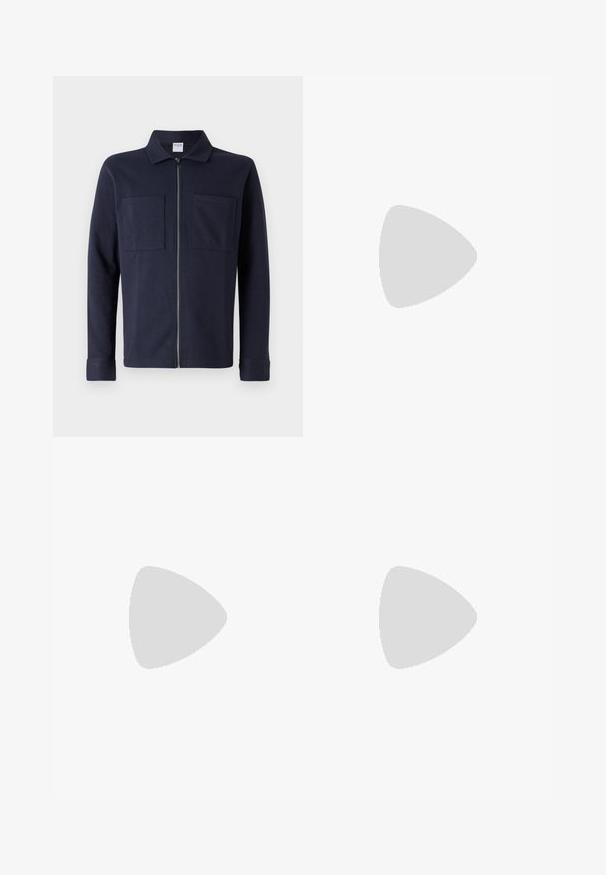 Casaco azul-marinho com fecho éclair, feito de algodão macio, apresentando um colarinho e dois bolsos frontais em patch. Textura suave com mangas longas.; Camisa de manga longa azul e branca com riscas, feita de algodão, apresentando um colarinho abotoado, botões frontais e um pequeno logotipo bordado no peito.; Calças bege com uma textura suave, corte reto, dois bolsos traseiros com botões e uma cintura padrão.; Sneaker preto com sola branca flutuando acima de um tapete texturizado bege, perto de uma mesa redonda de madeira com livros empilhados.