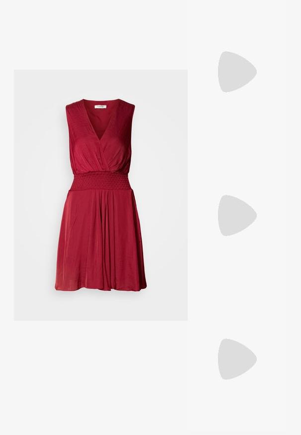 Robe rouge sans manches avec un décolleté en V profond, une taille smockée et une jupe fluide. Tissu doux et léger avec une texture subtile.; Bottes rouges, haute brillance, jusqu'aux cuisses, à bout pointu et talon aiguille. Présentent une fermeture éclair sur le côté et une finition lisse et élégante.; Pochette métallique argentée avec un design d'enveloppe angulaire, texture lisse et couleur intérieure contrastante, tenue dans une main portant un manteau noir.; Boucle d'oreille en argent avec une finition polie, présentant de petits détails en or et de forme ronde, portée sur le lobe.
