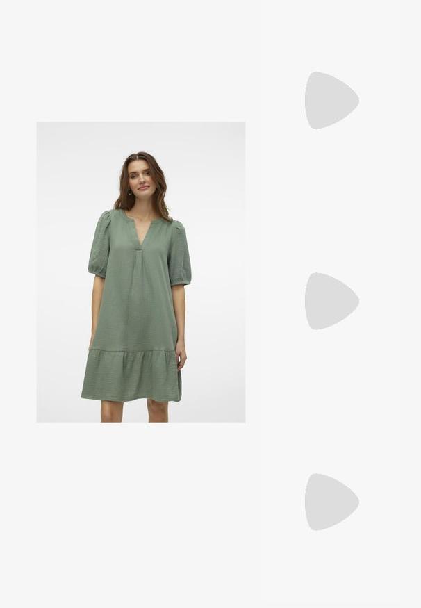 Zelena haljina širokog kroja s V-izrezom i kratkim puf rukavima. Ima višeslojni volanasti rub i teksturiranu tkaninu.; Crne lakirane kožne sandale s otvorenom petom i špicastim vrhom, s geometrijskom blok petom. Imaju elegantan, minimalistički dizajn i glatku teksturu.; Crna kožna torba s lukovitim oblikom, odvojivim remenom i zlatnim detaljima. Torba ima preklop s kopčom.; Prsten u zlatnoj nijansi s organskim, uvijenim dizajnom, glatkom teksturom i suženim krajevima, koji stvara moderan, skulpturalni izgled.