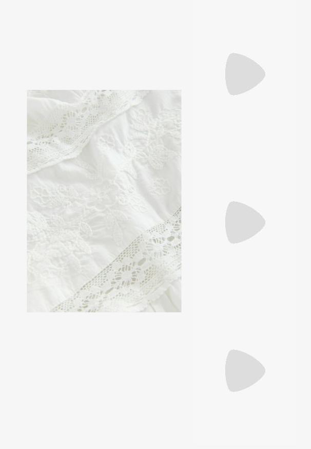 Tessuto bianco con ricami floreali complessi e delicati bordi in pizzo. Tessitura morbida con elementi di design a strati in tutto il tessuto.; Slingback bianco con punta affusolata, materiale superiore liscio, tacco basso a blocco e design con ritagli laterali, dotato di cinturino regolabile con fibbia.; Occhiali da sole rotondi con lenti scure e montatura dorata. Il modello indossa un cardigan leggero azzurro a costine con bottoni e maniche bianche a contrasto.; Wristlet Michael Kors in tela rivestita beige con motivo a logo MK ripetuto, hardware dorato e tracolla a catena staccabile.