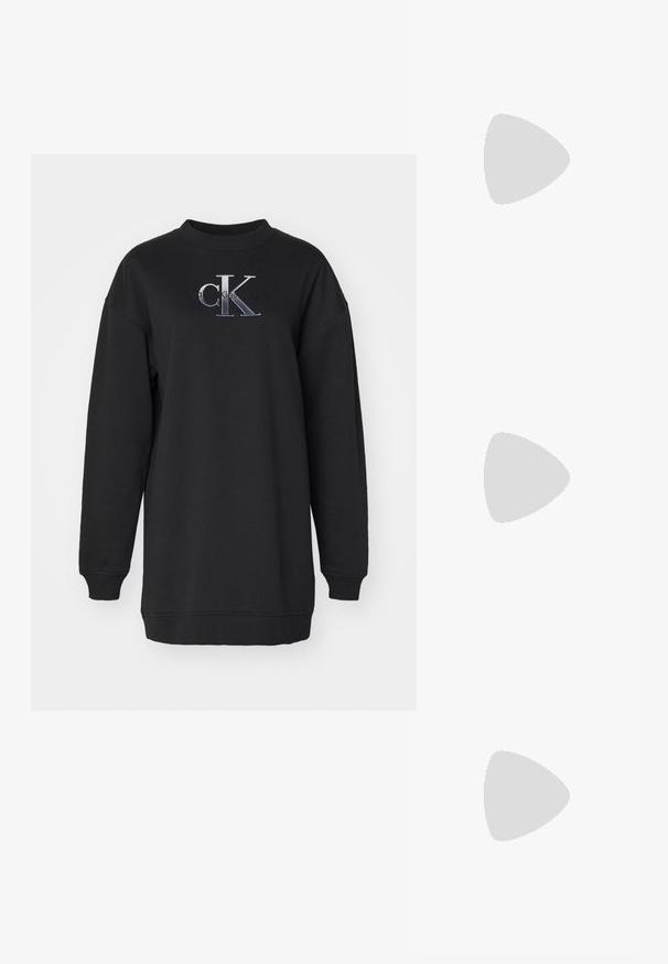 Svart sweatshirt i mjukt tyg, med rund halsringning, oversized passform, och broderad "CK"-logga i grått och vitt på framsidan.; Vita lädersneakers med en tjock vit sula, svartsuede hälaccent och präglad logotyp på sidan. Snörningsdesign med sex öglor.; Svart överdimensionerade solglasögon med geometrisk form, med mörka linser och en kontrasterande grå detalj på ramen. Logotyp på bygeln.; Silverfärgade hängande örhängen med en slät, blänkande yta. Rundad form, lätt design, med ett stift- och bakstängning.