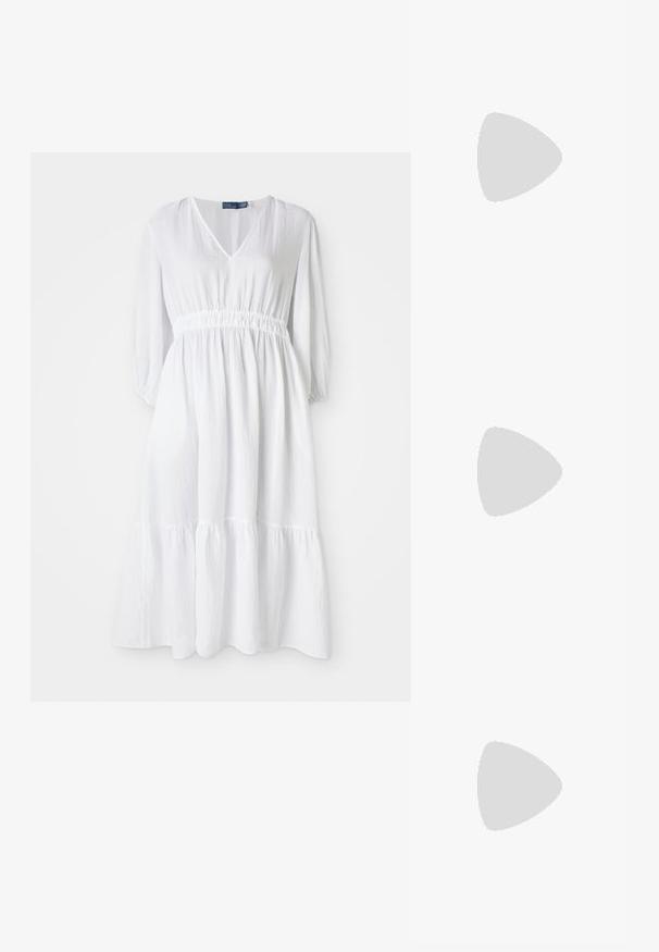 Robe blanche avec un décolleté en V, taille élastique et manches trois-quarts. Elle présente un ourlet à volants en couches et un tissu texturé.; Baskets en cuir blanc, design bas, avec une texture lisse, bout rond, lacets à l'avant et un petit logo brodé sur le côté.; Sac demi-lune en cuir noir avec des accents en métal doré, doté d'une fermeture éclair. Porté en bandoulière sur un pull gris.; Boucles d'oreilles avec clou en métal doré et design torsadé. Chaque boucle d'oreille est dotée d'un arrière transparent circulaire pour un port sécurisé.