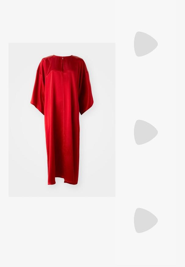 Piros kaftán ruha kerek nyakkivágással és rövid ujjakkal, sima anyagból készült, hátul függőleges cipzárral és laza fazonnal.; Fekete bokacsizma fényes bőrből, hegyes orral és díszes arany- és ezüstszínű részlettel az elején. Tömör sarok kialakítás.; Fekete steppelt bőr kézitáska gyűrt toppal, arany lánc vállpánttal és téglalap alakú formával, egyszerű háttér előtt tartva.; Ötvözött arany fülbevaló, kis díszítő kővel. Egy modelen látható, aki egyenes hajat visel, fehér, galléros inggel párosítva.