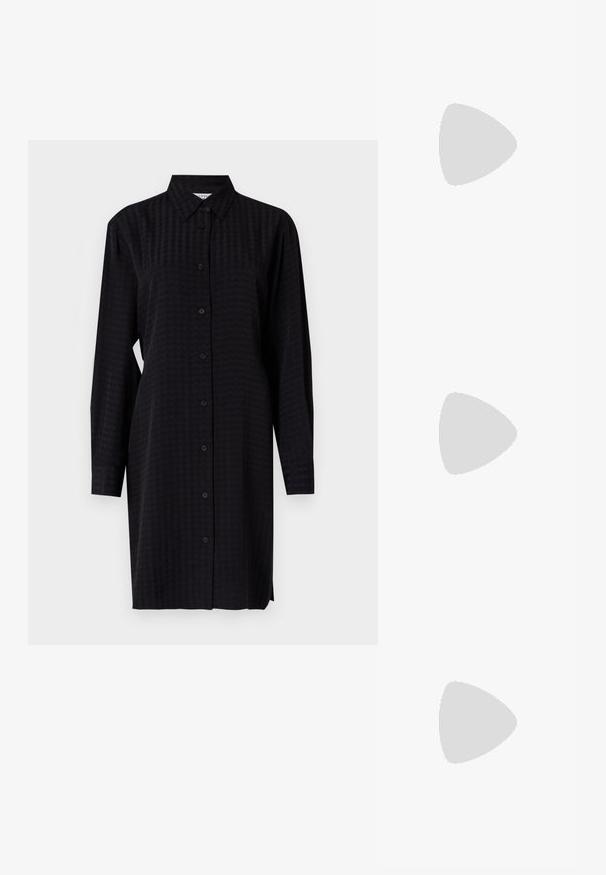 Robe chemise noire à boutons, à manches longues, en tissu texturé et à coupe droite, atteignant la mi-cuisse.; Baskets blanches en matériau synthétique lisse, avec un bout arrondi, un design à lacets, une semelle plate et des détails perforés discrets.; Sac à main noir à la forme structurée, texture lisse et fermoir métallique. Associé à un pantalon noir ample et des sandales ouvertes sur un sol en bois.; Boucles d'oreilles en argent avec une finition lisse et brillante. Forme arrondie, conception légère, avec un fermoir à tige.