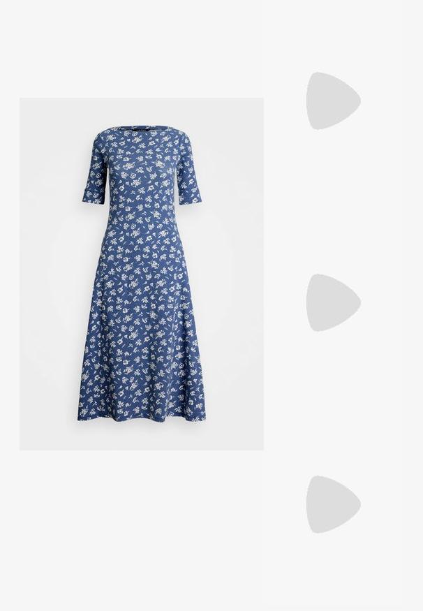 Blauwe bloemenjurk met korte mouwen, ronde hals en uitlopende taille. Gemaakt van zachte stof met een wit bloemenpatroon door het geheel.; Witte leren sneakers, laag model, met een gladde textuur, ronde neus, vetersluiting aan de voorkant en een klein geborduurd logo aan de zijkant.; Zwarte leren halfronde tas met een gouden hardware accent, voorzien van een ritssluiting. Draagt crossbody over een grijze trui.; Gouden knoopstuds met een gedraaide design. Elke oorring heeft een ronde transparante achterkant voor een veilige draagervaring.