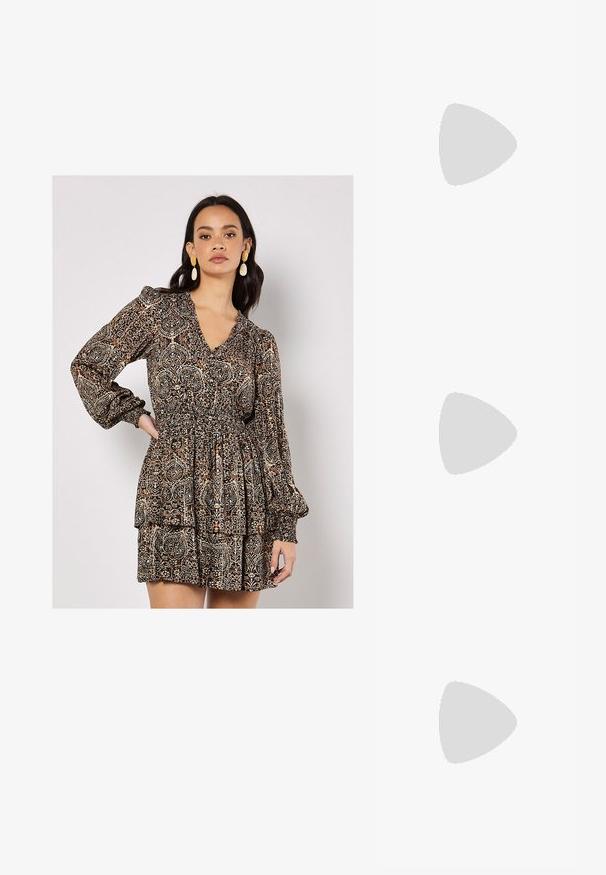 Langärmeliges Kleid mit V-Ausschnitt, gerafftem Taillenbund und geschichtetem Rock. Ausgestattet mit einem braun-beigen Paisleymuster und elastischen Bündchen.; Schwarzer Lackleder-Stiefelette mit spitzer Zehe und einem mittelhohen Blockabsatz. Glatte Textur und minimalistisches Design.; Schwarze übergroße Sonnenbrille mit getönten Gläsern, dicken Rahmen und goldfarbener Kettendetaillierung an den Bügeln.; Schwarze Handtasche mit strukturierter Form, glatter Textur und einem metallischen Verschluss. Kombiniert mit weiten schwarzen Hosen und offenen Sandalen auf einem Holzboden.