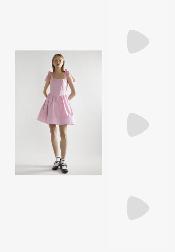 Rosa Baumwollkleid mit quadratischem Ausschnitt, gerafftem Rock und Bindebändern. Kombiniert mit schwarzen Mary Jane Schuhen und weißen Rüschenstrümpfen.; Schwarzer Lackleder Slingback-Schuh mit spitzem Zehenbereich, Knöchelriemen mit silbernen Schnallen und Beschlägen sowie einem schlanken Absatz.; Lila rechteckige Sonnenbrille mit dunklen, getönten Linsen, getragen mit einem pinkfarbenen, gemusterten Rollkragenpullover mit floralen Designs und lebhaften Akzenten.; Rosa strukturierte Handtasche aus strukturiertem Leder mit zwei Obergriffen, einem Klappverschluss und kontrastierenden Metallelementen.