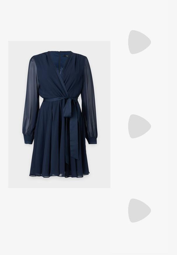 Mørkeblå omslagskjole med lange gjennomskinnelige ermer, belte i midjen og en flowy skjørt, laget av lett stoff. Glidelås i ryggen.; Sorte semskede plattformsandaler med bred klack, med krysslagte remmer og en spenne ved ankelen for en sikker passform.; Sølv metallisk clutch med et vinklet konvoluttdesign, glatt tekstur og kontrastfarge på innsiden, holdt i en hånd iført en svart kåpe.; Sølv hoops øredobber med en tvistet design, som har en polert finish og bakstøtte. Mål omtrent 3 cm i diameter.