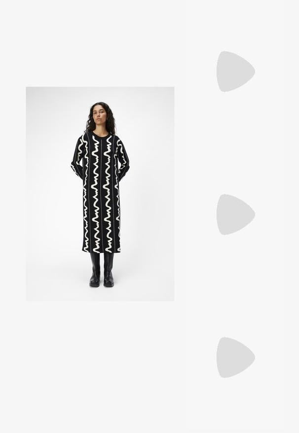 Robe longue noire avec des motifs ondulés blancs. Dispose d'un col rond et de manches longues. Assortie avec des bottes noires jusqu'aux genoux.; Bottes de cowboy en cuir marron avec un bout pointu et un talon bloc, présentant des coutures détaillées et des accents en relief sur la tige.; Lunettes de soleil style œil de chat avec une monture en écaille de tortue noire et orange, verres marron et pointes effilées et élégantes. Présente un logo minimaliste sur la branche.; Boucles d'oreilles en argent en forme de créoles avec un design torsadé, dotées d'une finition polie et d'une fermeture à poussoir. Mesurent environ 3 cm de diamètre.