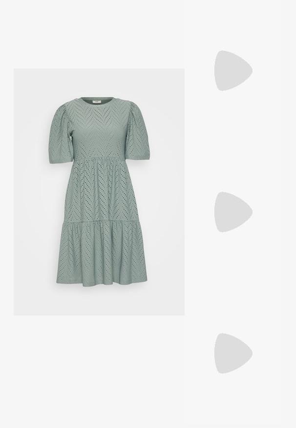 Vestido verde claro com mangas curtas bufantes, tecido texturizado com padrões em zigue-zague e detalhes recortados, saia rodada com bainha em camadas.; Sandalha metálica dourada com um salto em bloco angular, duas tiras sobre o pé e uma tira ajustável no tornozelo. Textura suave.; Mala sintética branca com formato triangular, aba frontal plana e detalhe de laço, alça ajustável, textura suave e design minimalista.; Brinco em metal dourado com um design elegante e curvo. Apresenta uma forma pontiaguda distinta, superfície polida e fecho por dobradiça.