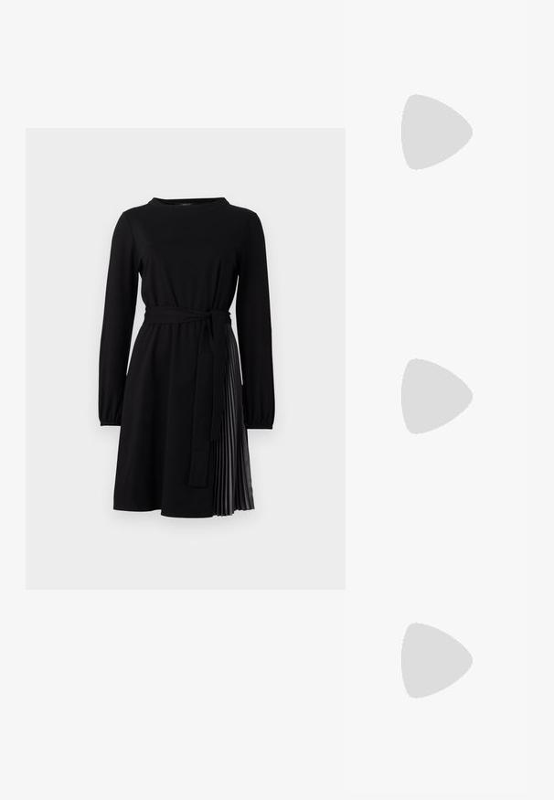 Black long-sleeve dress with a round neckline, fabric belt, and pleated skirt panel in a contrasting material. Smooth texture throughout.; Black leather ballet flat with a rounded toe, smooth texture, minimal stitching detail, and a flexible sole design.; Black leather half-moon bag with a gold hardware accent, featuring a zip closure. Worn crossbody over a gray sweater.; Gold-tone knot stud earrings with a twisted design. Each earring features a circular clear backing for secure wear.