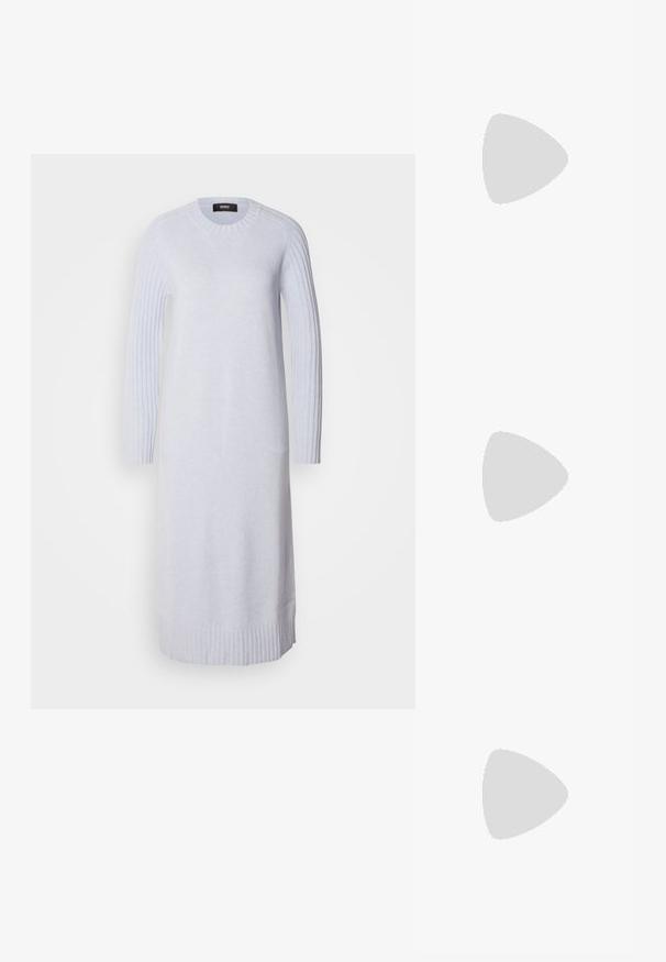 Vestido de malha cinza claro com mangas longas com sanefas e barra. Decote arredondado. Textura macia, silhueta reta, até ao joelho.; Sandal de pele preta com bico pontiagudo e um salto bloco baixo. Apresenta uma tira no tornozelo com uma fivela em tom dourado. Textura suave.; Óculos de sol oversized pretos com lentes degradê, armações grossas e detalhes em corrente dourada nas hastes.; Bolsa estruturada branca com alças curtas e uma alça de ombro, com detalhes em hardware dourado e material texturizado, exibida contra um fundo cinza.