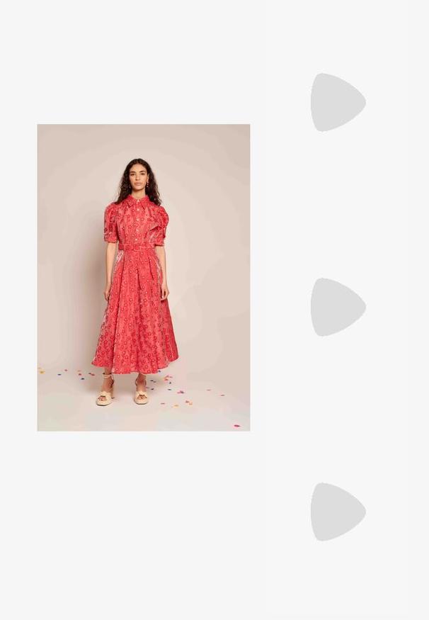 Kvinne med langt krøllet hår iført en rød blomstermønstret midikjole med pufferm, belte, kremfargede høyhælte sandaler, som står på et gulv dekket av konfetti.; Sorte skinnkne-høye støvler med spiss tå og høye stiletthæler. Glatt tekstur og elegant design, med minimal detaljering.; Svart skinn skulderveske med en buet form, polert sølvfeste og en avtakbar tag. Glatt tekstur med subtile sømdetaljer.; Øreringer i gulltone laget av metall, med en glatt, avrundet trikantform og stift-bakdesign; reflekterende overflate med minimal detaljer.