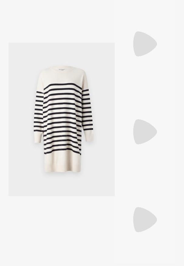 Vestido de suéter crema com riscas pretas, mangas longas, punhos canelados e decote arredondado. Textura suave; comprimento até aos joelhos.; Sabrinas de cerâmica preta com salto bloco, bico apontado e um design com recortes arredondados. Apresenta um detalhe em fivela de tom dourado.; Óculos de sol oversized pretos com lentes degradê, armações grossas e detalhes em corrente dourada nas hastes.; Bolsa preta com forma estruturada, textura suave e um fecho metálico. Combinada com calças largas pretas e sandálias de salto aberto sobre um chão de madeira.