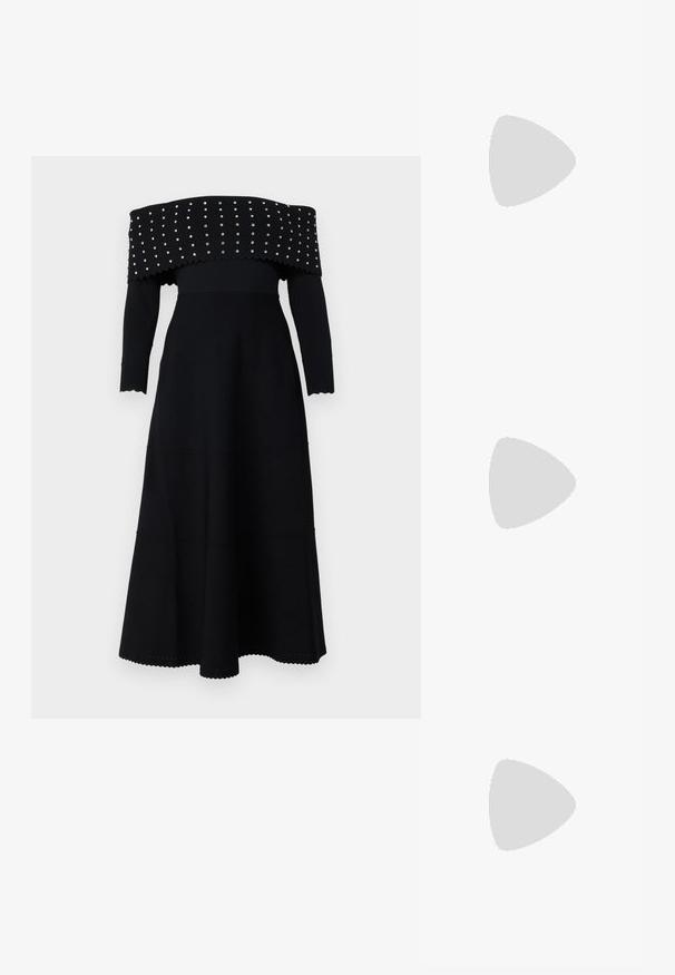 Juodas off-the-shoulder suknelė su ilgomis rankovėmis, raukšlėta tekstūra, banguotais kraštais ir sidabriniais knopkėmis išilgai kaklo ir krūtinės.; Baltos odinės sportbačiai, žemo profilio, su lygia tekstūra, apvalia nosimi, raištelių sistema priekyje ir mažyte siuvinėta logo šone.; Juodas odinis pusmėnulis krepšys su auksinėmis detalėmis, turintis užtrauktuko uždarymą. Dėvimas per petį ant pilko megztinio.; Aukso spalvos mazgo auskarai su sukimo dizainu. Kiekvienas auskaras turi apvalų skaidrų pagrindą, užtikrinantį saugų dėvėjimą.