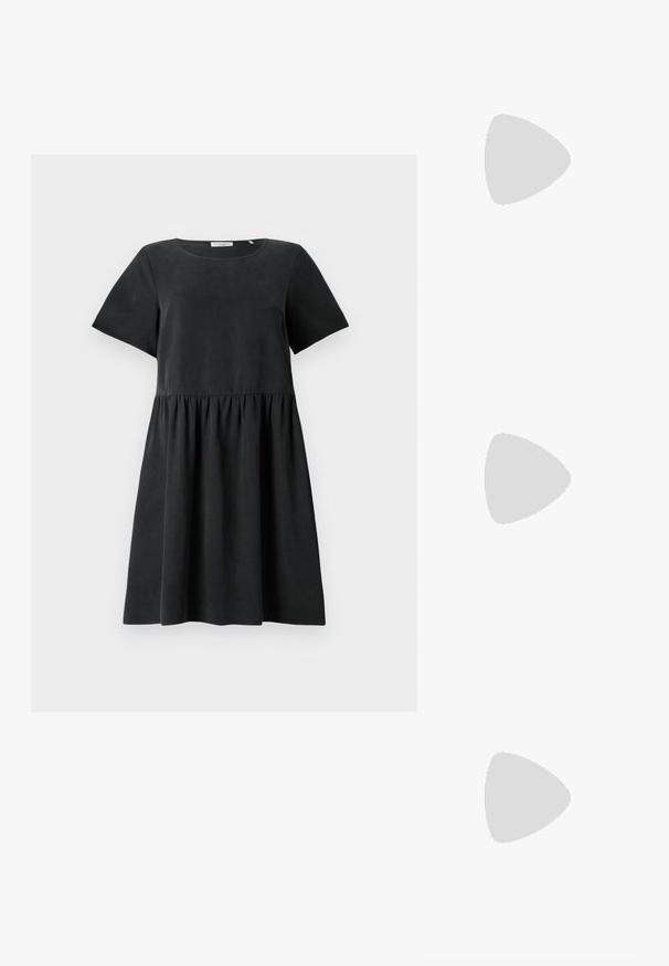 Schwarzes Kurzarmkleid mit einem runden Halsausschnitt, strukturiertem Stoff und einer gerafften Taille, die eine ausgestellt Silhouette schafft.; Schwarze Lackleder-Slingback-Absätze mit spitzer Zehenform, einem runden Ausschnitt-Design und einem Blockabsatz. Mit einem goldfarbenen Schnallenakzent.; Schwarze übergroße Sonnenbrille mit getönten Gläsern, dicken Rahmen und goldfarbener Kettendetaillierung an den Bügeln.; Schwarze Handtasche mit strukturierter Form, glatter Textur und einem metallischen Verschluss. Kombiniert mit weiten schwarzen Hosen und offenen Sandalen auf einem Holzboden.