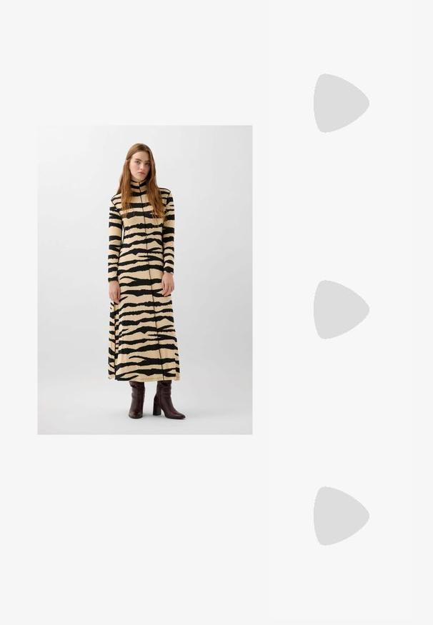 Beige maxidress met zwarte tijgerstrepen, met een hoge hals, lange mouwen en een comfortabele pasvorm. Gemaakt met kniehoog bruine laarzen.; Bruine suède ballerina's met een spitse neus, platte zool en een gladde textuur. Strak ontwerp zonder zichtbare hardware of accenten.; Zwarte vierkante zonnebril met een matte afwerking, voorzien van transparante lenzen en een lichte blauwe tint aan één kant. Stevig, hoekig ontwerp.; Bruine en crèmekleurige koeienhuid schoudertas met een gladde leren band, ritssluiting en een zachte, tekstuursurface met een natuurlijk patroon.