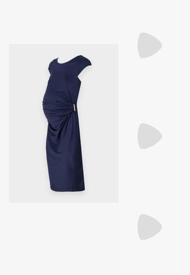 Tengerészkék kismama ruha rövid ujjakkal, elöl ráncolt részletezéssel és arany díszítéssel a deréknál. Simá, rugalmas anyag.; Fekete lakk bőr, pántos magassarkú cipő, hegyes orral, lekerekített kivágással és tömbsarkal. Arany színű csat díszíti.; Fekete, oversize napszemüveg fokozatos árnyalatú lencsékkel, vastag kerettel és arany színű lánc díszítéssel a szárakon.; Fekete kézi táska strukturált formával, sima textúrával és fémből készült záródással. Széles fekete nadrággal és nyitott orrú szandállal párosítva, fából készült padlón.