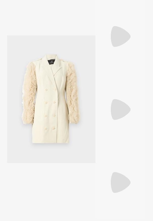 Blazer doppiopetto color crema con maniche beige trasparenti e arricciate. Presenta bottoni grandi e una vestibilità sagomata. Design semplice ed elegante.; Scarpa con tacco alto in vernice nera, cinturino alla caviglia regolabile e punta affilata, con lati aperti. Texture liscia.; Occhiali da sole neri oversize con lenti sfumate, montatura spessa e dettagli in catena dorata sulle astine.; Borsa nera con forma strutturata, texture liscia e una chiusura metallica. Abbinata a pantaloni neri larghi e sandali open-toe su un pavimento in legno.