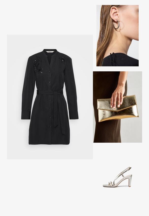 Svart skjortekjole laget av bomull med belte i livet, knappelukking foran, og smakfulle blomster-sequin detaljer på skuldrene.; Metallisk sølv høye hæler sandal med åpen tå, med tre tynne stropper over foten og en ankelstropp med spenne.; Gull metallisk clutch-veske med en glatt tekstur, som har en trekantet klaffelukking. Hånden som holder den har pent manikyrte negler.; Sølv ringøredob med en polert finish, med små gull detaljer og en rund form, båret på øreflippen.