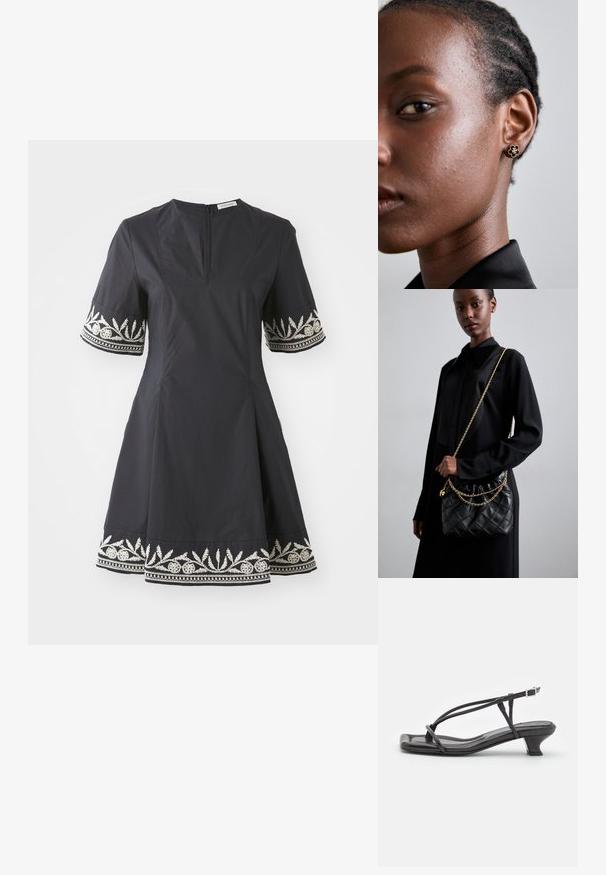 Černé šaty s přiléhavým korzetem, rozšířenou sukní a krátkými rukávy, které mají na manžetách a lemu propracované vyšívané bílé květinové vzory.; Černé kožené sandály s tenkými pásky, nízkým blokovým podpatkem a čtveratou špičkou. Obsahují přezku a mají hladkou texturu.; Černá prošívaná kožená kabelka s staženým vrchem, zlatým řetízkovým popruhem a obdélníkovým tvarem, držena před jednoduše pozadím.; Zlaté květinové náušnice mají texturované černé střed a jemné detaily. Modelova jasná pleť a splétané vlasy jsou viditelné v profilu.