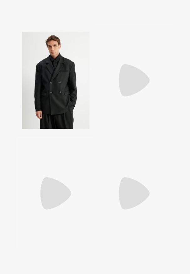 Koton Blazer - black; Jonge man met krullend lichtbruin haar, in een zwart T-shirt met korte mouwen en grijze broek, kijkt naar links met zijn handen in zijn zakken.; Beige op maat gemaakte broek met een subtiel ruitpatroon, gemaakt van lichte stof, met zijzakken en een rechte pijpdesign.; Zwarte leren instapper met een ronde neus, gestikte details en een decoratieve band aan de voorkant. Platte zool met een minimaal profiel.