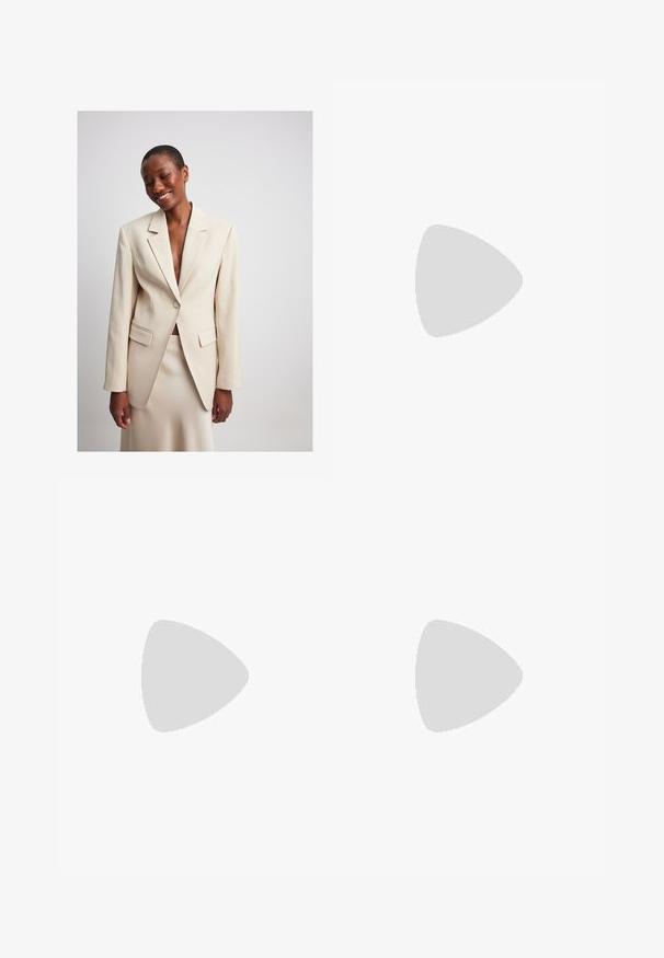 NA-KD Blazer - champagne; En enkel vit t-shirt i bomull med rund halsringning, korta ärmar och en avslappnad passform. Slät textur utan mönster eller detaljer.; Kvinna som står med händerna på höfterna klädd i en figurnära grå kortärmad polotröja, ljusblå vida jeans och grå spetsiga skor.; Röda lackläderklackskor med öppen tå, böjd ovandel och smal klack. Slät yta med en glansig finish och en minimalistisk design.; Svart vävd tote-väska med två handtag. Mjuk textur, slapp design och en stor, rundad form. Inga synliga detaljer eller accenter.