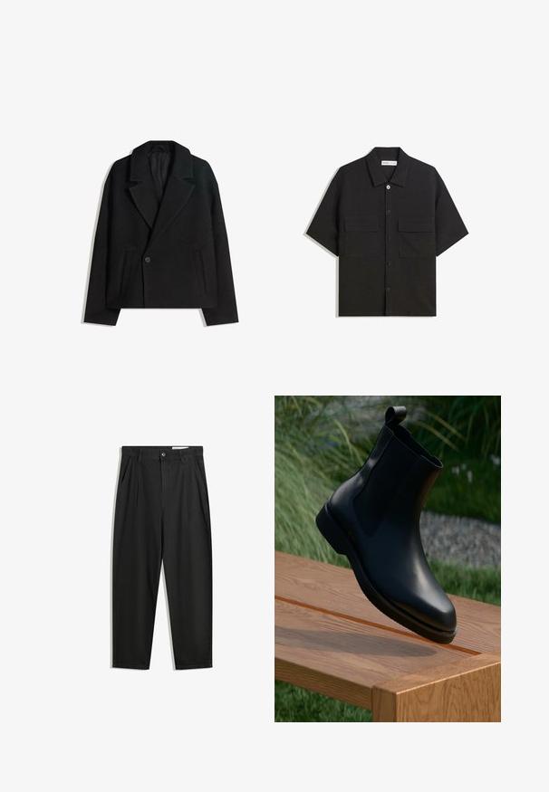 Cappotto doppiopetto in misto lana nera con rever strutturati, due tasche laterali e chiusura a un bottone. Tessuto morbido e testurizzato.; Camicetta nera a maniche corte realizzata in tessuto con una trama liscia, presenta due tasche frontali, un colletto classico e chiusura con bottoni.; Pantaloni in cotone neri con una vestibilità rilassata, dotati di una vita classica, pieghe frontali e tasche laterali. Tessuto liscio senza fantasie.; Stivali ankle in pelle nera con finitura liscia, pannelli laterali elasticizzati e un linguetta sul gambale, posati su una superficie di legno.