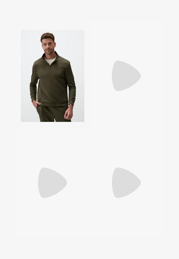 Olijfgroene sweatshirt met een halve rits kraag, gemaakt van een gladde stof, met lange mouwen en een relaxte pasvorm. Opvallende stikdetails.; Beige broek met een rechte snit, voorzien van een enkele zwarte knoop, riemlussen en zijzakken. Glad stoffen textuur en een minimalistisch ontwerp.; Witte sportschoen met een bovenwerk van mesh, zwarte accenten en zilveren details. Beschikt over een gevoerde zool en een vetersluiting voor extra ondersteuning.; Zwarte rechthoekige zonnebril met groene lenzen, voorzien van een matte afwerking, rechte pootjes en het Ray-Ban-logo aan de zijkant.