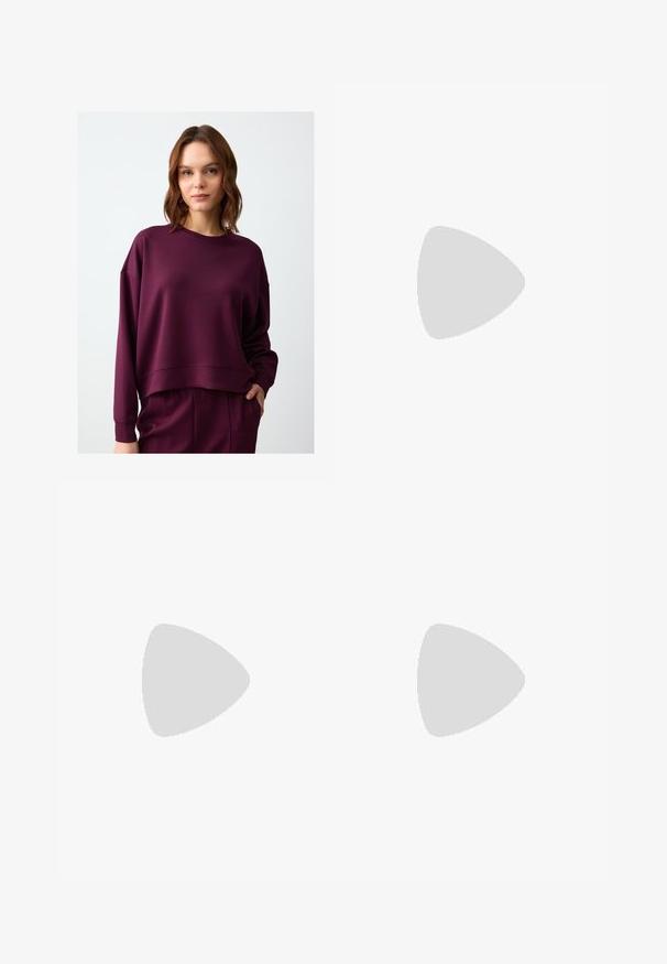 Felpa corta bordeaux con maniche lunghe, scollatura rotonda e polsini a costine. Tessuto morbido e strutturato con vestibilità comoda.; Pantaloni larghi blu navy in tessuto morbido, con pieghe frontali, passanti per cintura e tasche laterali. Include una chiusura a bottone in vita.; Scarpe sportive con tomaia in pelle bianca, punta in suede grigia e tre strisce nere. Presentano un logo blu sulla linguetta e una suola in gomma testurizzata.; Borsa a tracolla in pelle bordeaux con forma curvata, una sola tracolla e dettagli cuciti al centro. Texture liscia, hardware minimale.