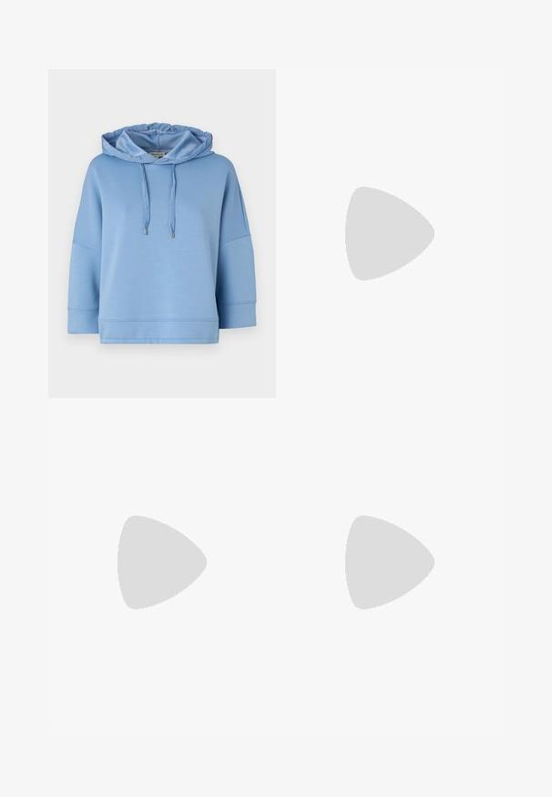 Felpa leggera blu con cappuccio regolabile, vestibilità ampia, maniche corte e texture liscia e morbida. Presenta cuciture minime e dettagli argentati.; Jeans in denim a gamba larga di colore blu profondo, con dettaglio cucitura frontale, chiusura con bottone e design classico a cinque tasche.; Sneaker bianchi realizzati in materiale a rete, suola in gomma, design senza lacci con bande elastiche e dettagli in tonalità oro.; Borsa a tracolla nera in pelle con una forma curva, manico rimovibile e accessori dorati. La borsa presenta una patta con un dettaglio a fibbia.