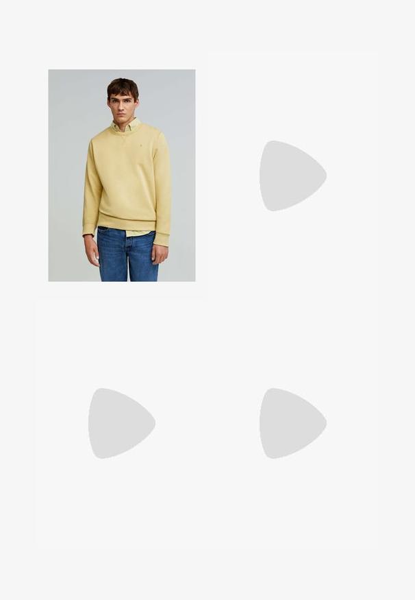 Scalpers - Bluza; Ciemnoniebieskie dżinsy o dopasowanym kroju, zdobione plamkami farby, widocznymi szwami oraz standardowym pięciopocketowym designem. Prosto cięte nogawki.; Białe skórzane sneakersy o gładkim wykończeniu, okrągłym nosku, płaskich sznurówkach i teksturowanej podeszwie. Charakteryzują się delikatnym logo na pięcie.; Czarne okrągłe okulary przeciwsłoneczne z ciemnymi soczewkami i smukłymi metalowymi ramkami. Zawierają przezroczyste końcówki zauszników oraz srebrne akcenty przy zawiasie. Minimalistyczny design.