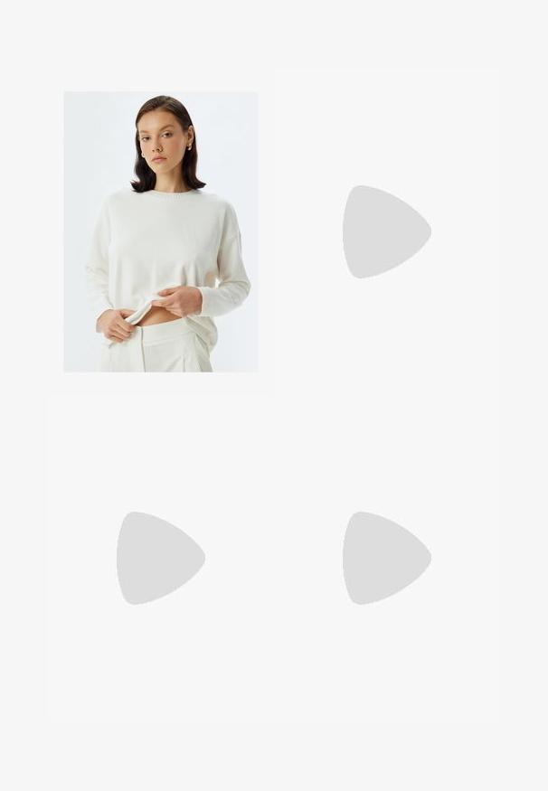 Maglione in crema a maglia con maniche lunghe e scollatura a costine, abbinato a pantaloni coordinati. Il tessuto sembra morbido e leggero.; Jeans in denim azzurro chiaro con taglio a gamba larga, dettagli strappati, design a cinque tasche e chiusura con zip.; Stivali neri al ginocchio in pelle liscia, con punta appuntita, tacco a blocco e un'apertura a forma di V nella parte superiore.; Occhiali da sole tartarugati marroni con forma vintage a occhio di gatto e lenti marroni. Presentano bracci curvi con accenti rossi.