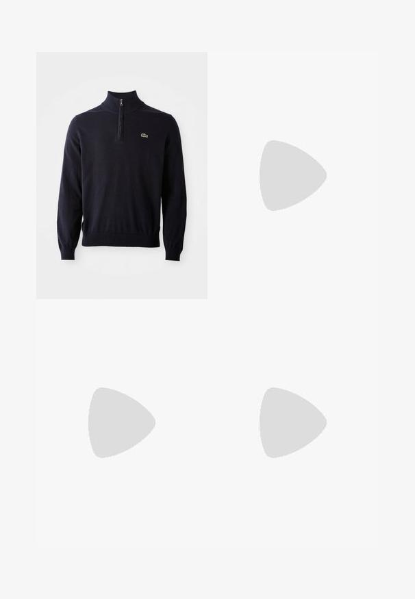 Sötétkék pulóver negyedcipzárral, bordázott mandzsettákkal és szegéllyel, puha anyagból készült, a mellrészen egy kis zöld krokodil logóval.; Fehér pamut póló kerek nyakkal, rövid ujjakkal és bal oldali mellzsebbel. Oldalvarrásán található egy kis logós cimke.; Fehér pamut nadrág, egyenes szabással, két elülső plissével, egy gombos záródással és oldalsó zsebekkel. Sima textúra.; Fekete sneakers fehér talppal lebeg egy bézs textúrájú szőnyeg felett, egy kerek fából készült asztal közelében, rajta egymásra pakolt könyvekkel.