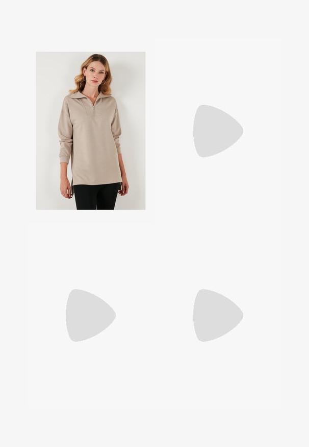 Pulóver beige con media cremallera en la parte delantera, cuello oversized, mangas largas y aberturas laterales. Tejido suave con un ajuste relajado.; Pantalones negros de pierna ancha hechos de una tela suave y brillante, con una cinturilla elástica y sin bolsillos visibles ni detalles de metal.; Zapatillas de lona negras con cordones blancos, puntera de goma blanca y una suela blanca gruesa. Presenta costuras blancas sutiles y una suela de goma.; Gafas de sol negras rectangulares con lentes oscuros y montura gruesa mate. Las varillas son ligeramente cónicas con una textura suave.