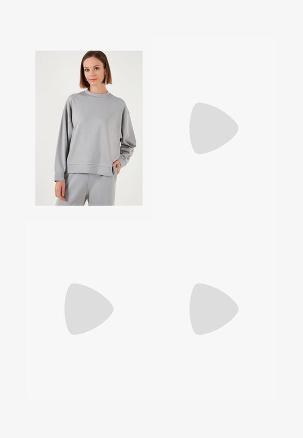 Ljusgrå sweatshirt i mjukt material, med rund hals, sänkta axlar och ribbade manschetter. Slät textur med minimala designdetaljer.; Grå randiga byxor med en avslappnad passform, med en enknapps-knäppning, veck och en vid byxdesign.; Svart knälång kjol med sidoklyv, kombinerad med svarta loafers och genomskinliga bruna strumpbyxor, med en slät textil och enkel design.; Silverörhängen med en slät, polerad yta och en tunn, cirkulär form. Designen har en säker låsning.