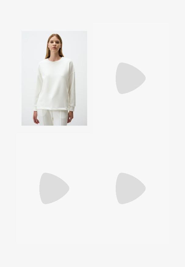 Witte sweatshirt met ronde hals, lange mouwen, een relaxte pasvorm en geribde manchetten en zoom. Soepele textuur en minimalistisch ontwerp.; Ruime broek in donkergroen stof, met een geplooide voorkant, een knoopsluiting en een gepolijste, gestructureerde afwerking.; Zwarte rubberen flip-flop sandaal met een getextureerde strap en een eenvoudige platte zool, zijaanzicht op een effen lichte achtergrond.; Bruine gevlochten leren tote bag met geknoopte handvatten, gedragen door een persoon in lichtblauwe spijkerbroek en zwarte Chunky schoenen. Gladde, textuurrijke oppervlakte.