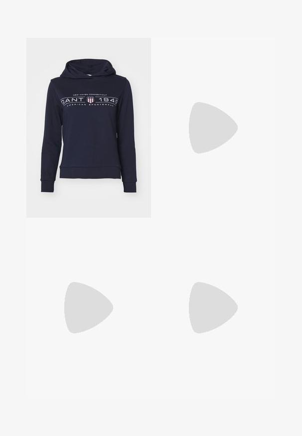 Felpa con cappuccio blu navy realizzata in tessuto misto cotone, con colletto alto, maniche lunghe e una grafica frontale con dettagli di testo e logo.; Jeans a vita alta blu chiaro con gamba larga, chiusura frontale con bottone e zip, tasche anteriori e posteriori, su uno sfondo bianco.; Stivale alla caviglia in camoscio marrone con rivestimento morbido color crema, cerniera laterale e suola in gomma spessa. Presenta una texture liscia e punta arrotondata.; Borsa a tracolla in pelle marrone con forma curvata, hardware dorato e un dettaglio con fibbia. Presenta una tracolla rimovibile.