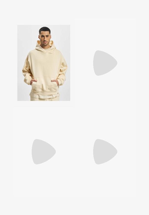 Hoodie beige surdimensionné en tissu doux, avec une grande poche frontale et une capuche avec cordon de serrage. L'ourlet inférieur comporte une étiquette de marque.; Pantalons de lounge en coton gris avec une taille élastique, un cordon de serrage et deux poches latérales ; design à jambe droite, texture douce, sans motifs.; Bottine en daim beige avec un col rembourré noir, œillets en métal doré, détails de surpiqûres blanches et semelle en caoutchouc robuste avec des crampons prononcés.; Lunettes de soleil avec une monture légère en plastique gris clair, au design enveloppant, lentilles sombres et texture lisse. Présentent un marquage minimal sur le côté.