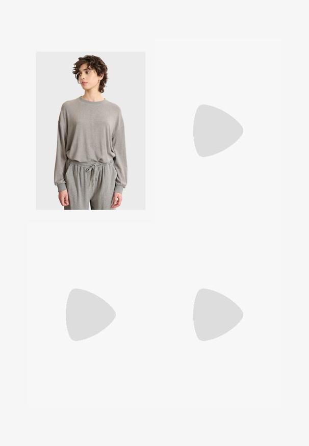 Giovane con i capelli corti e ricci che indossa un ampio maglione grigio chiaro e pantaloni coordinati con coulisse, mentre guarda di lato.; Jeans neri a gamba larga con vita alta, dotati di due tasche frontali e dettagli in metallo sui bottoni. Il tessuto ha una texture liscia.; Sneakers bianche con strisce nere e accenti in suede beige. Presentano una suola in gomma texturizzata e lacci bianchi piatti, indossate con calzini di colore chiaro.; Borsa a tracolla nera realizzata in materiale sintetico testurizzato. Presenta un design con logo inciso e una tracolla regolabile. Chiusura con zip.