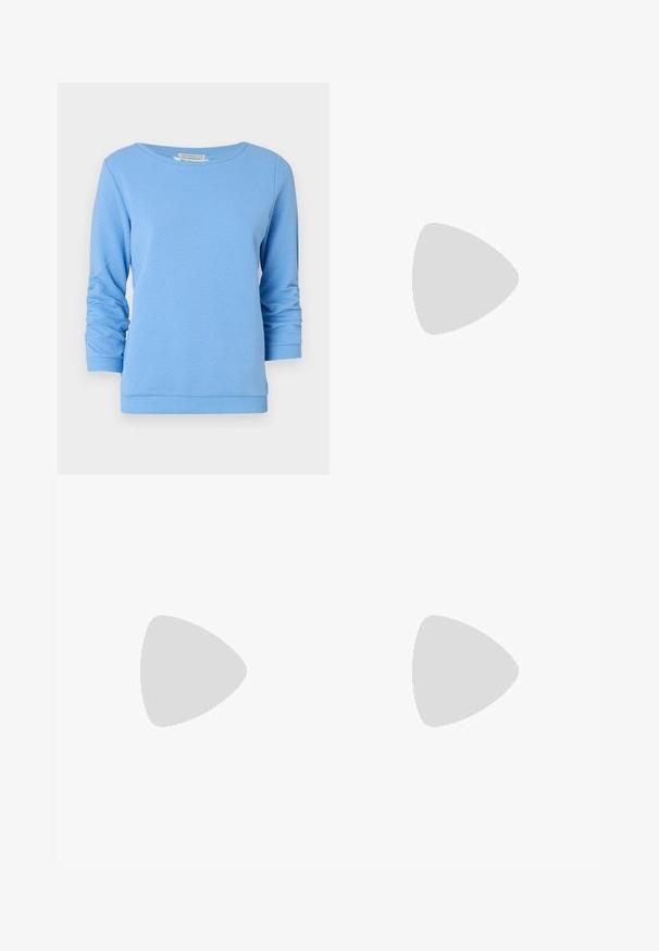 Jasnoniebieska bluza z dzianiny bawełnianej o teksturowanej strukturze. Posiada dekolt typu łódka, długie rękawy z podwiniętymi mankietami oraz prążkowany dół.; Granatowe spodnie o szerokich nogawkach, wykonane z miękkiego materiału, z przodem w kant, gładką fakturą i prostym krojem bez widocznych kieszeni.; Jasnoróżowe baleriny na odkrytej pięcie z wąskim noskiem, wykonane z gładkiego materiału imitującego skórę. Posiadają wycięcia po bokach oraz płaski obcas.; Biała skórzana torebka o strukturalnym wzorze, z magnetycznym zapięciem i paskiem na ramię, zaprezentowana na neutralnym tle.